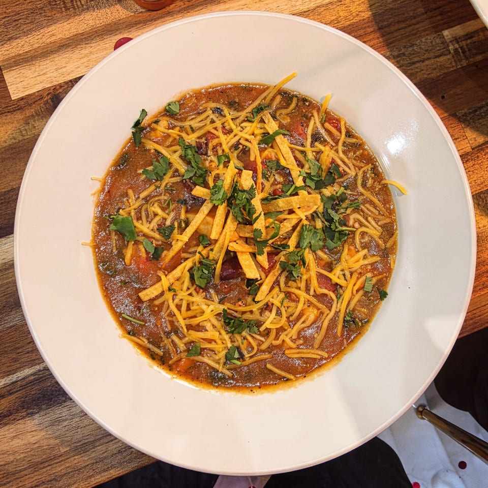 Savory crepe dish from The Crepe Lab, topped with shredded cheese, tortilla strips, and fresh cilantro.